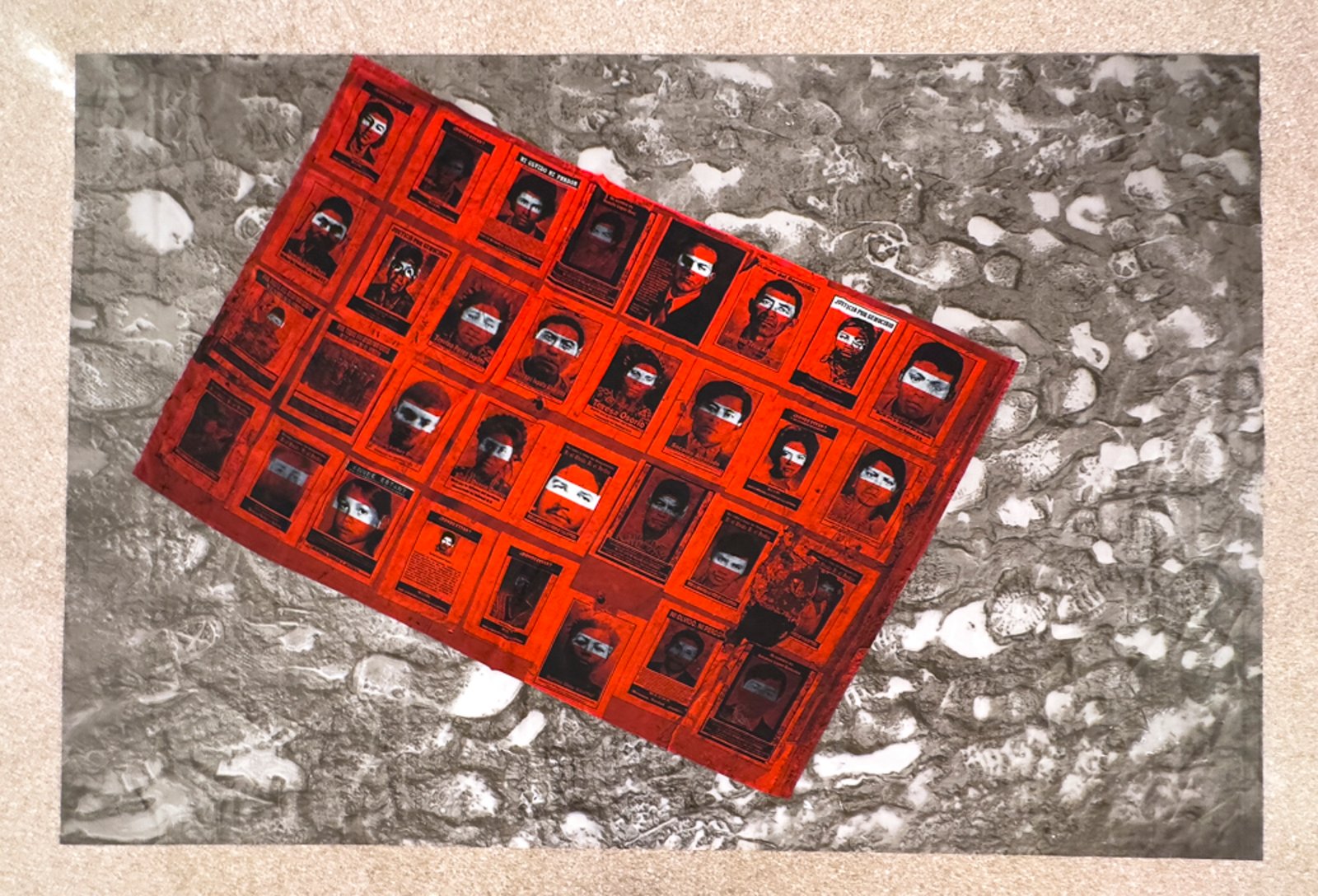 The Disappeared — red grid of portraits with a white band masking the eyes, sublimation on polyester sateen laid on the floor over an archival inkjet print on polyester tarp