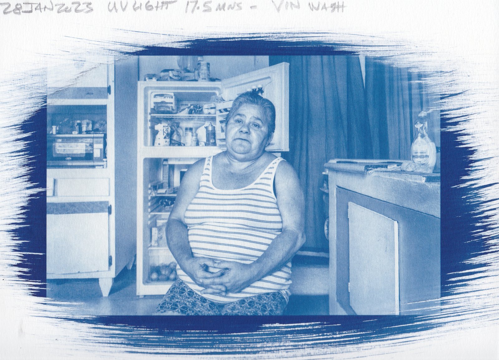 Paper test — older man with hands clasped, soft kitchen light, vinegar-toned cyanotype on paper, 18min UV exposure, 28 Jan 2023